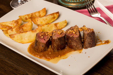 Close up of forest animal steak with potatoes and a glass of win