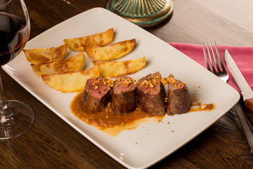Close up of forest animal steak with potatoes and a glass of win