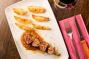Close up of forest animal steak with potatoes and a glass of win