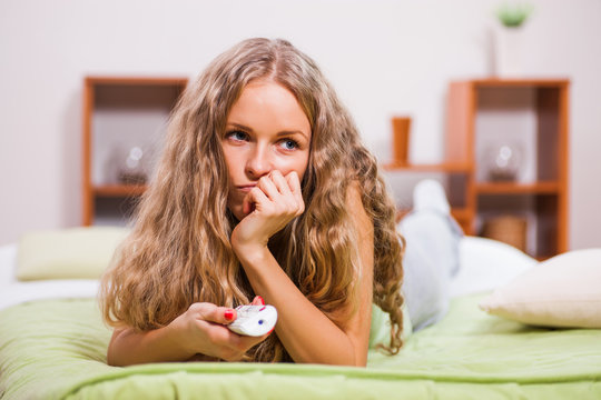 Young Woman Is Lying In Bed And Watching TV.