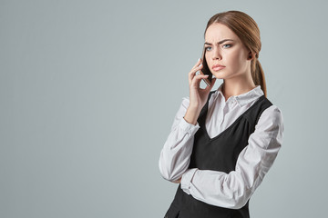 Young girl talking at the cellphone on a gray background