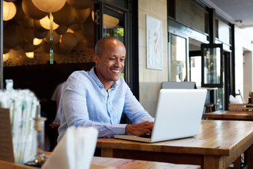 smiling businessman sitting at table with laptop