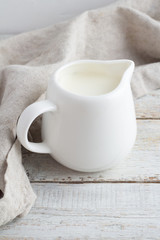 White milk jug with milk on a white background