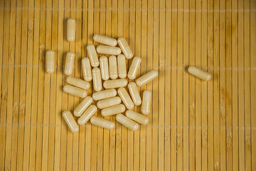 Drugs capsule. White pill medicines an a wooden