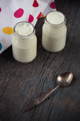 jars with white yogurt and spoon on the wooden background