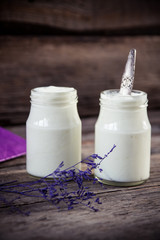 Yogurt in jar on the wooden table with purple dried plant