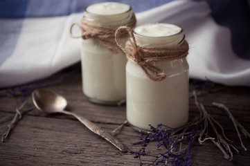 yogurt in jars on the wooden table with napkin, spoon and dried