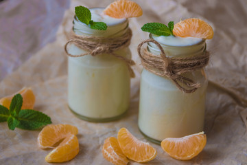 Organic yougurt with fresh tangerine and mint in glass jars