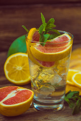 Fresh lemonade in a glass beaker with ice, green mint, red orang