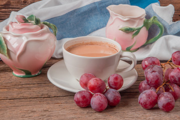 Still life with cup of coffee witj milk, red grapes, pink crocke