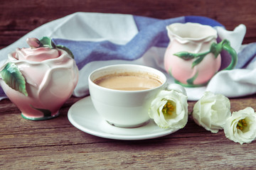 Cup of coffee with milk, red grapes, pink crockery and eustomas