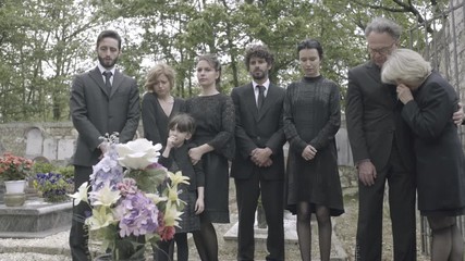 Mourners standing around grave - Powered by Adobe