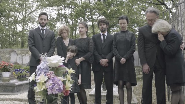 Mourners standing around grave