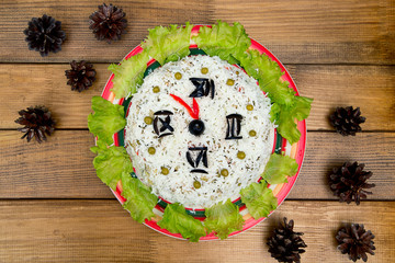 The Christmas salad rice olives greens peas - concept New year clock face, midnight, brown wooden background spruce cones on the table.