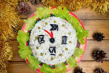 the Christmas salad rice olives greens peas - concept New year clock face, midnight, brown wooden background spruce cones tinsel on the table.