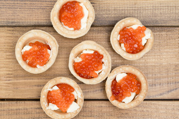 the Several tartlets with red caviar and butter on wooden brown table top view