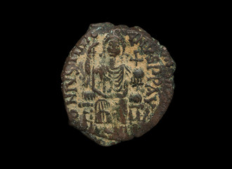 Ancient copper Byzantine copper coin with figure on it isolated on black