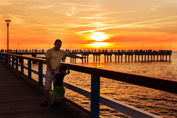 pier on the sea. sunset. Palanga. father and son walking along the waterfront
