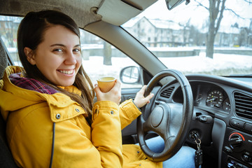 Charming businesswoman drinking cup while driving to work