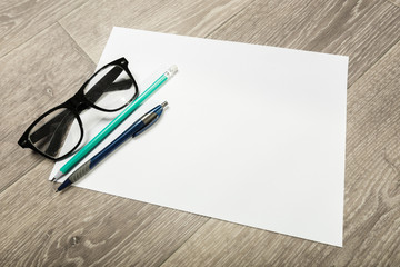 Blank notebook and pencil with glasses on wooden table