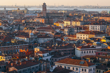 Fototapeta na wymiar Aerial view of Venice, Italy, at sunset with rooftops of buildings and warm sunlight.
