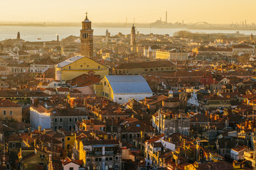 Aerial view of Venice, Italy, at sunset with rooftops of buildings and warm sunlight.
