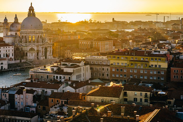 Fototapeta premium Aerial view of Venice, Italy, at sunset with rooftops of buildings and warm sunlight.