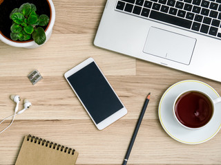 Wooden table with a smartphone, computer and a Cup of tea. The view from the top