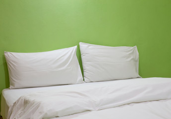 An unmade bed with white linens background green