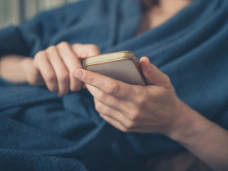 Woman in bathrobe using smartphone