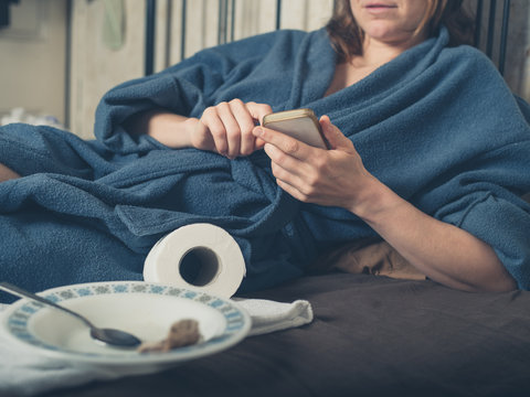 Ill woman in bed using smartphone