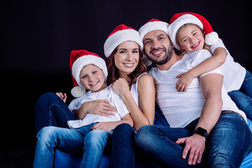 Fototapeta na wymiar family in Santa hats looking at camera