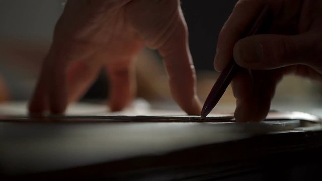 Closeup view of craftsman's hands working with a piece of leather on the table