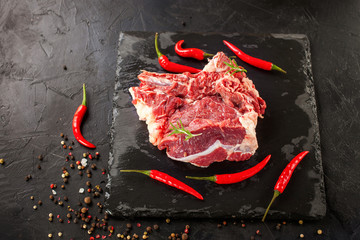 piece of raw meat of beef on a board with spices, selective focus, copy space, dark photo