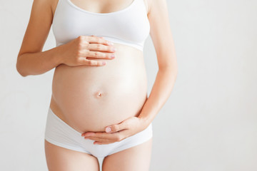 Pregnant woman in white underwear. Young woman expecting a baby.