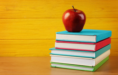 Books and apple on wooden background