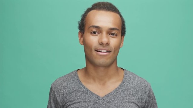 Handsome afro american man doing different flirt expressions and looking at camera isolated on the green background