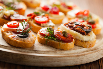Crostini with different toppings on wooden background. Delicious appetizers. Front view.