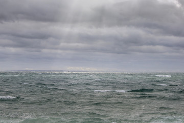 Fototapeta premium Sunrays on a stormy ocean
