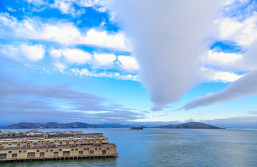 Alcatraz Island Beyond San Francisco Piers Under Nice Clouds