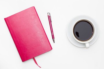 Cup of black coffee and diary with pen