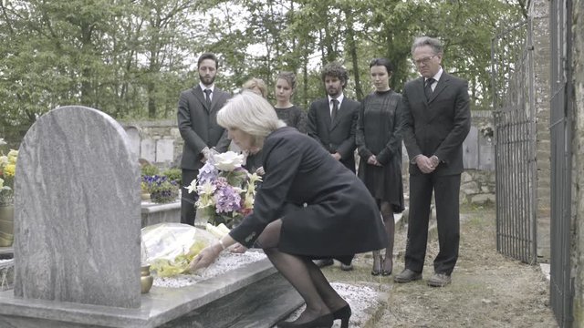 Senior woman laying flowers on grave