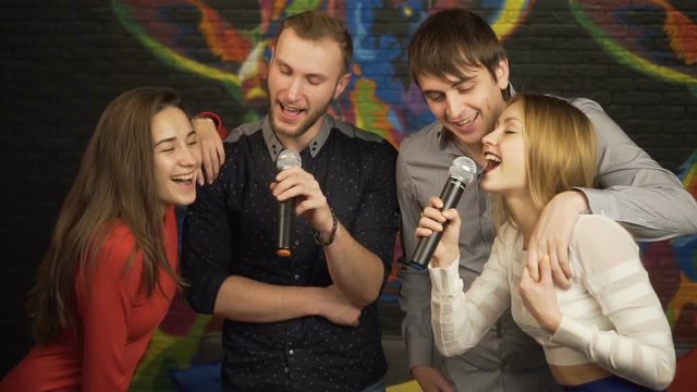 Group of friends singing karaoke in a nightclub. Slow motion.