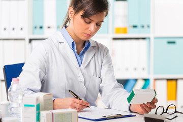 Female pharmacist sat at desk writing notes