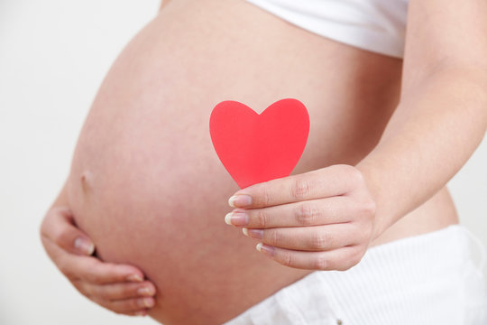 Close Up Of Pregnant Woman Holding Heart Shape