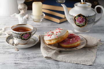 Breakfast with donut and cup of tea. Old books on table