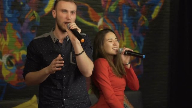 Guy and a girl singing in a karaoke club. Slow motion.