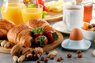 Breakfast consisting of croissants, coffee, fruits, orange juice