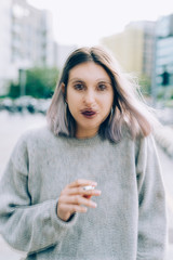 Double exposure of young beautiful caucasian purple grey hair woman outdoor in the city smoking a...