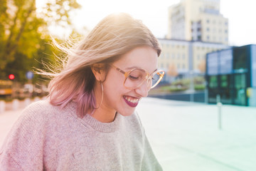 Portrait of young beautiful caucasian purple grey hair woman outdoor in the city looking at camera, smiling - happiness, carefree, serene concept